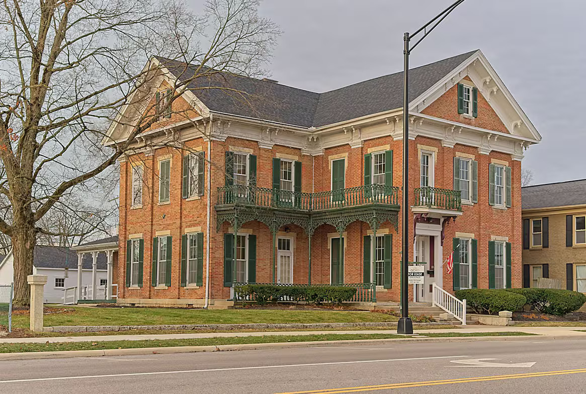 Front facade of the historic brick building with Victorian balconies and green shutters