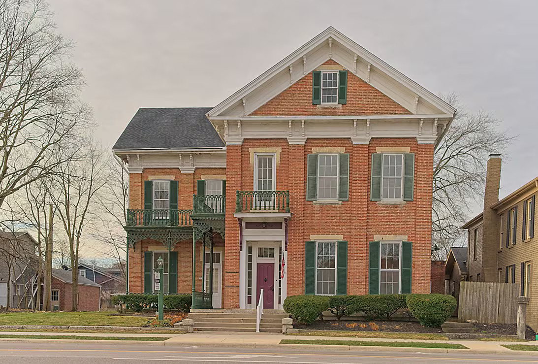 Street view of the historic brick building with arched entry and shuttered windows