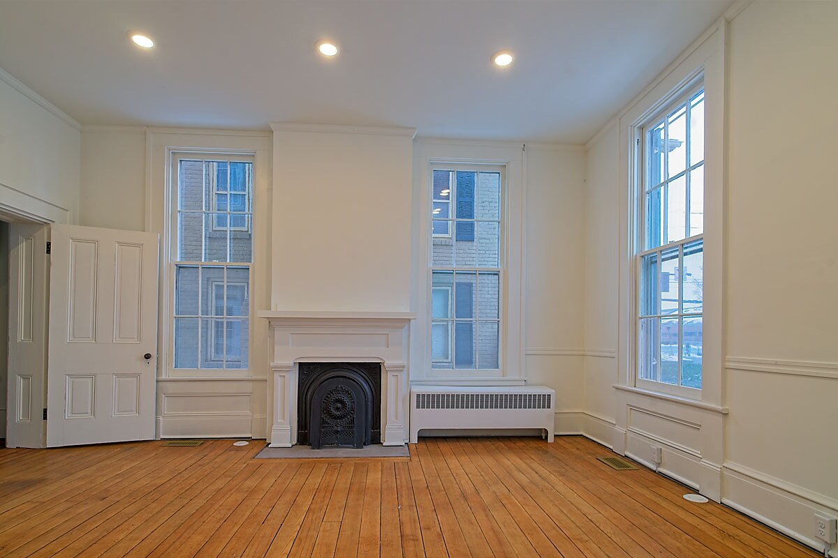 Bright room with original marble fireplace, tall windows, and hardwood floors