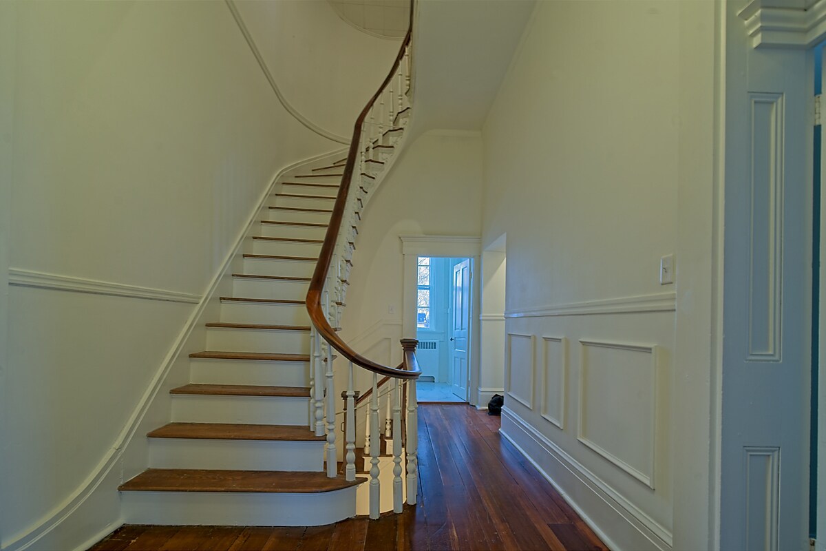 Curved grand staircase with original banister and wainscoted hallway