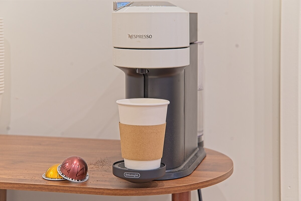 Nespresso machine with a fresh latte on a wooden side table