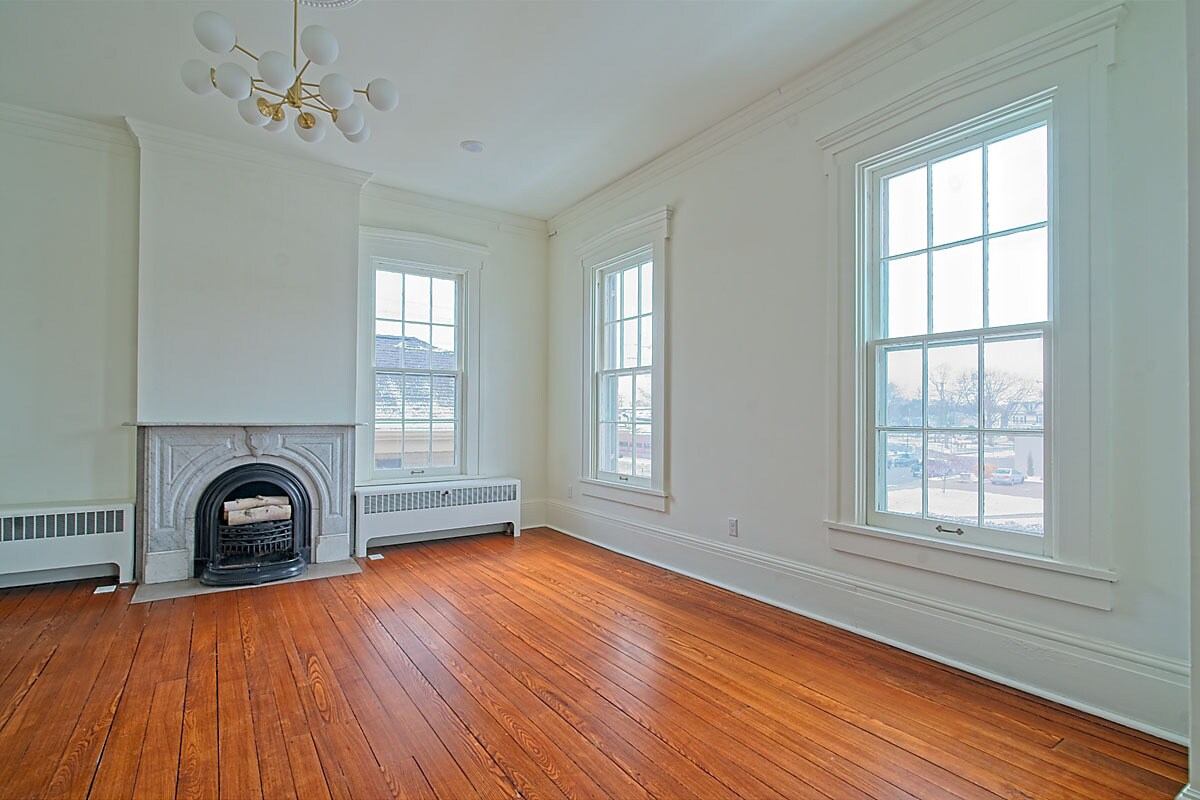 Sunlit room with fireplace, chandelier, and three windows overlooking downtown Troy