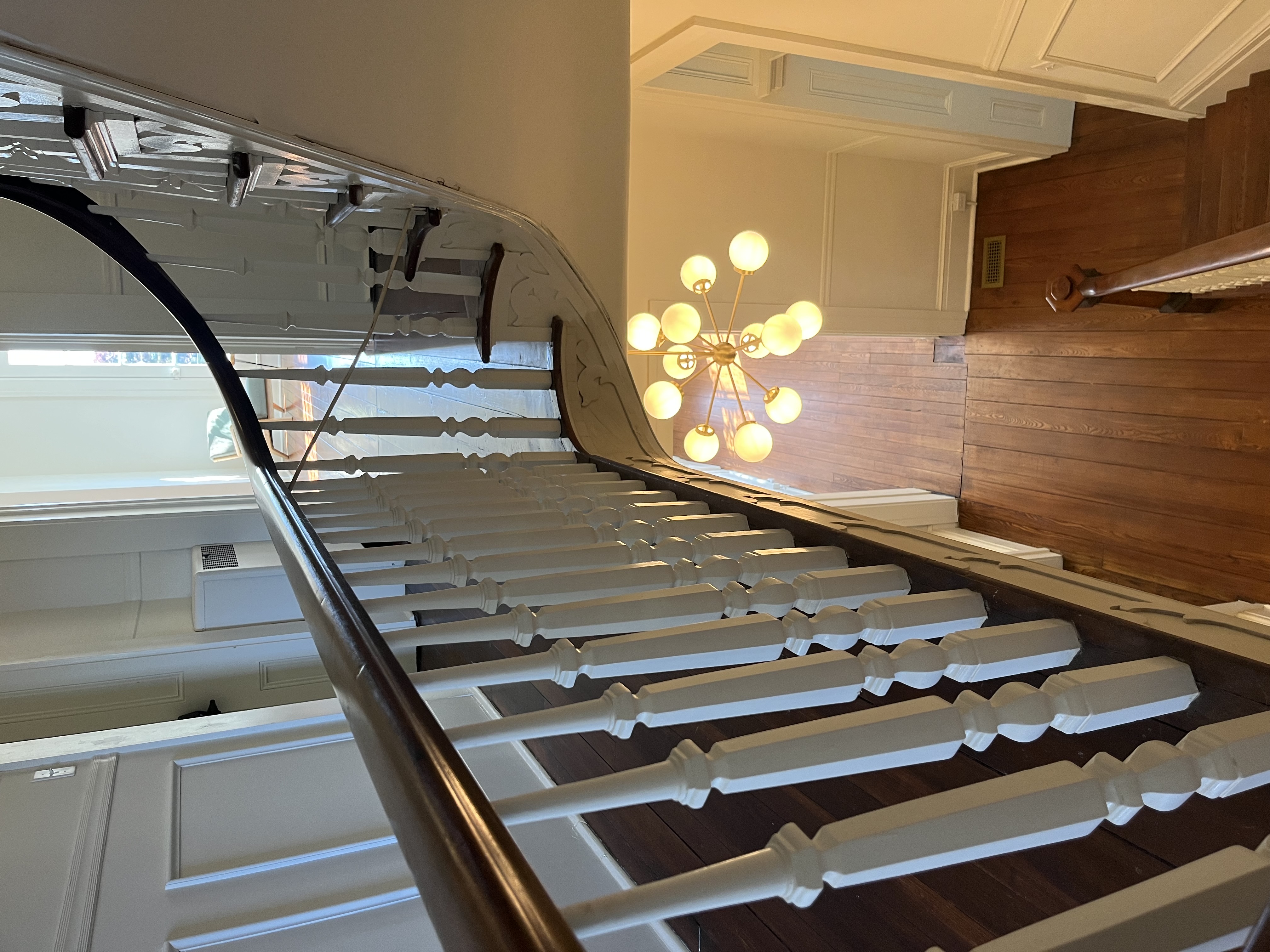 Grand curved staircase with original banister and Sputnik chandelier